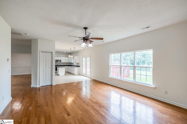 19 Hartwell Dr, Simpsonville, SC 29681 - unfurnished living room featuring light wood-type flooring, baseboards, ceiling fan, and a textured ceiling