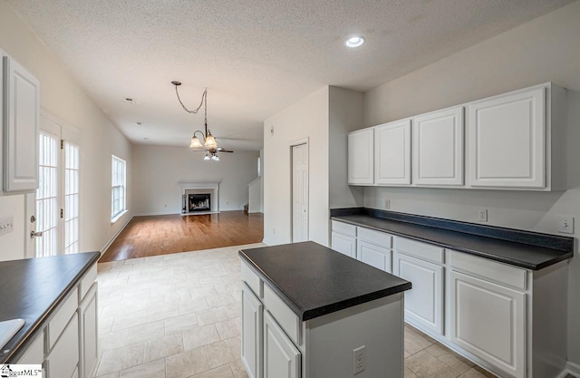 19 Hartwell Dr, Simpsonville, SC 29681 - kitchen with dark countertops, white cabinets, a textured ceiling, a chandelier, and open floor plan