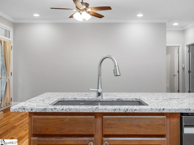 251 Saddlebrook Dr, Moore, SC 29369 - kitchen view of a sink, brown cabinetry, crown molding, ceiling fan, and light stone countertops