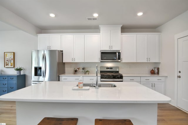 105 Boren Way, Greenville, SC 29607 - kitchen featuring appliances with stainless steel finishes, white cabinets, a kitchen bar, tasteful backsplash, and an island with sink