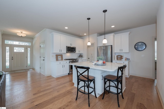 26 Bradstock Dr, Greer, SC 29650 - kitchen featuring stainless steel appliances, light countertops, a breakfast bar, light wood finished floors, and white cabinets