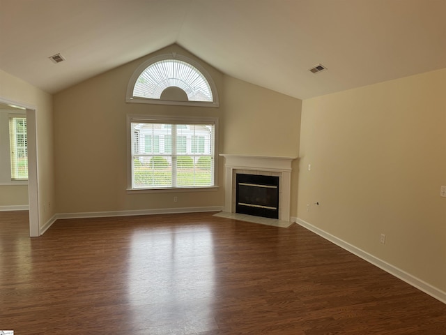 unfurnished living room with plenty of natural light, dark wood-style flooring, a tiled fireplace, and vaulted ceiling