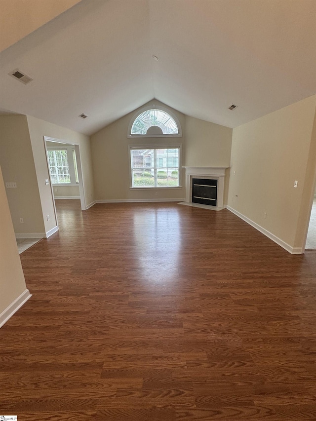 unfurnished living room featuring dark wood finished floors, lofted ceiling, baseboards, and a fireplace with flush hearth