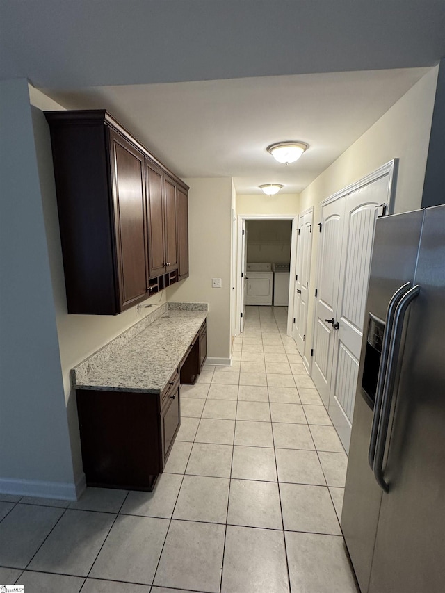 laundry area featuring washing machine and clothes dryer, light tile patterned floors, and baseboards