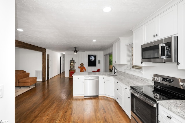 502 Hunts Bridge Rd, Greenville, SC 29617 - kitchen featuring appliances with stainless steel finishes, a peninsula, open floor plan, wood finished floors, and white cabinetry