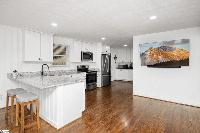502 Hunts Bridge Rd, Greenville, SC 29617 - kitchen featuring appliances with stainless steel finishes, a peninsula, dark wood finished floors, white cabinetry, and recessed lighting