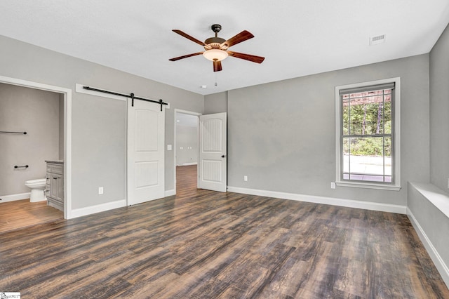 1061 Hidden Glory Dr, Landrum, SC 29356 - unfurnished bedroom featuring a barn door, wood finished floors, baseboards, ensuite bath, and a ceiling fan