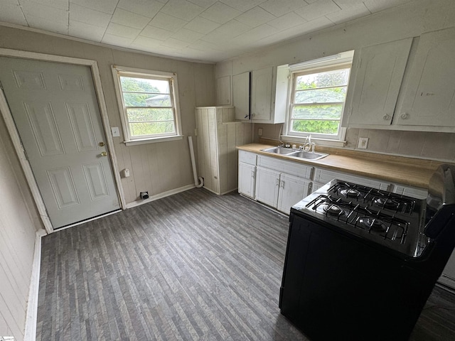 403 Duckett St, Laurens, SC 29360 - kitchen featuring black range with gas cooktop, a sink, plenty of natural light, white cabinets, and wooden walls