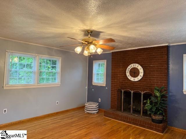 3444 Geer Hwy, Marietta, SC 29661 - unfurnished living room featuring a textured ceiling, wood finished floors, a ceiling fan, crown molding, and a fireplace
