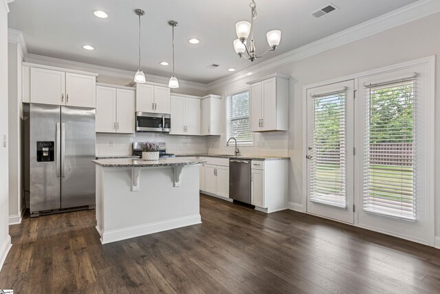 122 Rivermill Pl, Piedmont, SC 29673 - kitchen with appliances with stainless steel finishes, light stone countertops, white cabinetry, backsplash, and ornamental molding