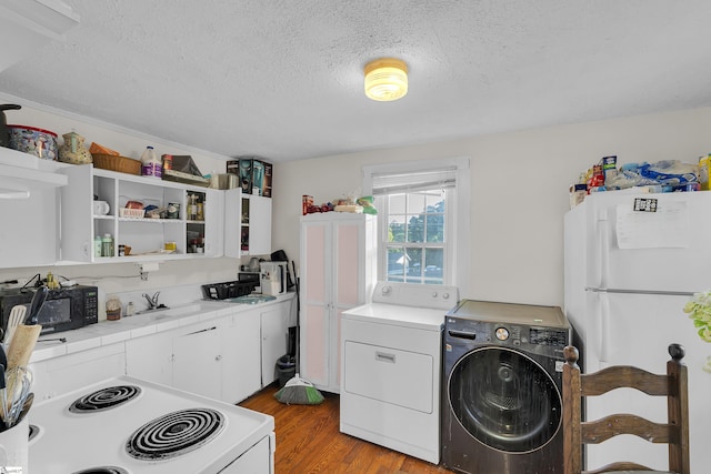 2413 Andrews Rd, Spartanburg, SC 29302 - kitchen featuring washer / dryer, white appliances, a textured ceiling, light wood-style floors, and white cabinetry