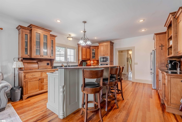 251 W Mcelhaney Rd, Taylors, SC 29687 - kitchen featuring appliances with stainless steel finishes, brown cabinets, a kitchen island, light wood-style flooring, and a breakfast bar area