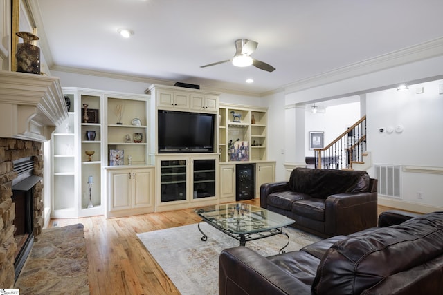 116 Legends Way, Simpsonville, SC 29681 - living area with a ceiling fan, a stone fireplace, light wood-type flooring, ornamental molding, and beverage cooler