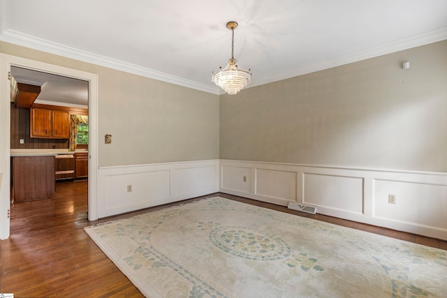 21 Kensington Rd, Greenville, SC 29617 - spare room featuring crown molding, dark wood finished floors, a chandelier, a wainscoted wall, and a decorative wall