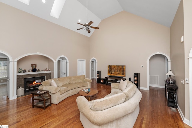 3 Swamp Lily Ct, Simpsonville, SC 29681 - living room featuring high vaulted ceiling, arched walkways, wood finished floors, a premium fireplace, and a skylight