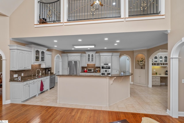 3 Swamp Lily Ct, Simpsonville, SC 29681 - kitchen with arched walkways, appliances with stainless steel finishes, a sink, glass insert cabinets, and a high ceiling