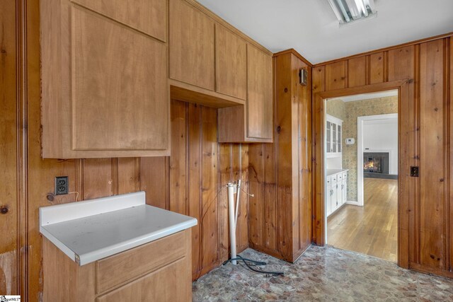 611 E S 6th St, Seneca, SC 29678 - kitchen with a lit fireplace, wood walls, light countertops, and brown cabinets
