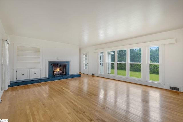 611 E S 6th St, Seneca, SC 29678 - unfurnished living room featuring built in features, light wood-style floors, and a lit fireplace