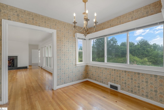 611 E S 6th St, Seneca, SC 29678 - unfurnished dining area with baseboards, light wood-style flooring, a chandelier, wallpapered walls, and a fireplace with raised hearth