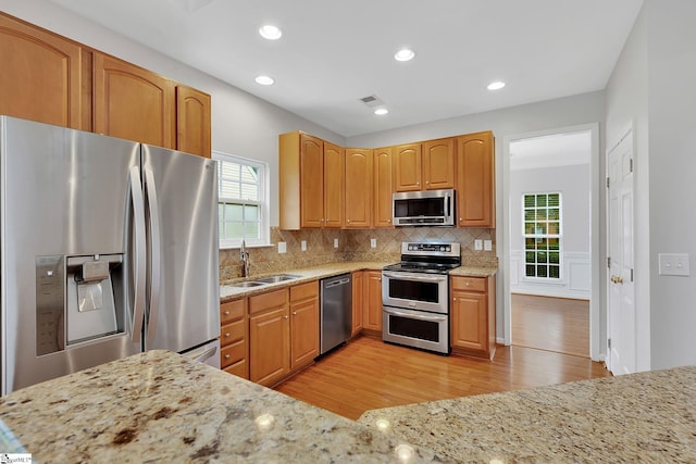 100 Beason Farm Ln, Simpsonville, SC 29681 - kitchen featuring stainless steel appliances, a sink, light wood finished floors, light stone countertops, and decorative backsplash