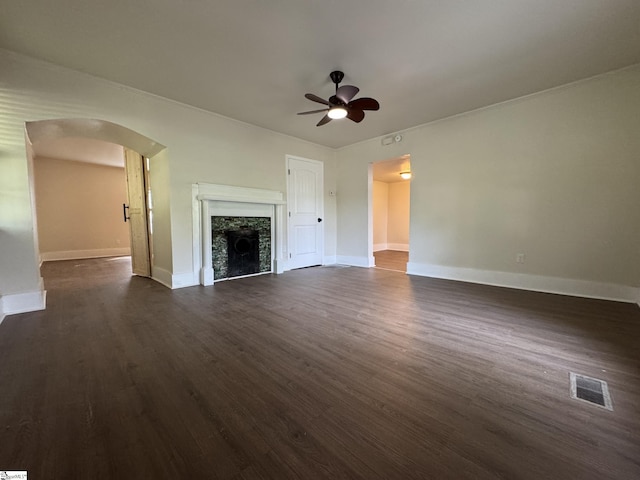 800 W Hampton St, Laurens, SC 29360 - unfurnished living room with arched walkways, ceiling fan, baseboards, dark wood finished floors, and a fireplace