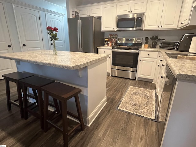 383 Amelia Springs Ln, Moore, SC 29369 - kitchen with stainless steel appliances, dark wood-style floors, white cabinets, light countertops, and a center island