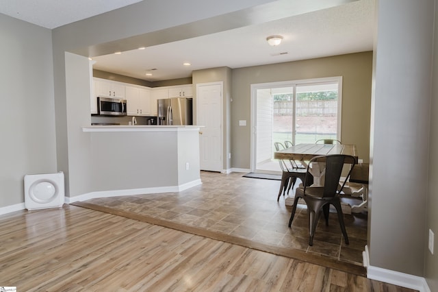 48 Border Ave, Simpsonville, SC 29680 - kitchen featuring appliances with stainless steel finishes, light wood-style flooring, white cabinetry, and a peninsula