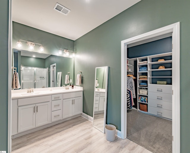 345 Cypress Hollow Trl, Piedmont, SC 29673 - bathroom with double vanity, a shower stall, a walk in closet, wood finished floors, and baseboards