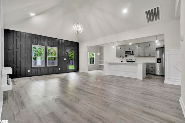 1708 Old Georgia Hwy, Gaffney, SC 29341 - unfurnished living room featuring a chandelier, high vaulted ceiling, light wood-type flooring, a sink, and a decorative wall
