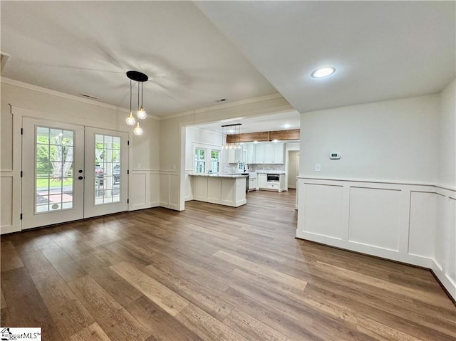 800 Holiday Dam Rd, Honea Path, SC 29654 - unfurnished living room featuring french doors, a decorative wall, crown molding, wood finished floors, and wainscoting