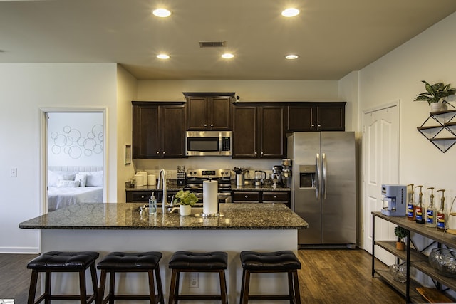 350 Hartleigh Dr, Lyman, SC 29365 - kitchen with appliances with stainless steel finishes, a breakfast bar, dark brown cabinetry, dark wood finished floors, and dark stone countertops