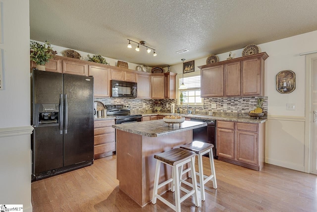 809 Dove Creek Ct, Boiling Springs, SC 29316 - kitchen with black appliances, light wood finished floors, tasteful backsplash, a center island, and a textured ceiling