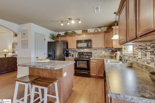 809 Dove Creek Ct, Boiling Springs, SC 29316 - kitchen with black appliances, a sink, light wood-style floors, a kitchen bar, and a center island