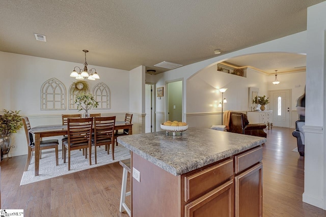 809 Dove Creek Ct, Boiling Springs, SC 29316 - kitchen featuring arched walkways, wood finished floors, open floor plan, a kitchen island, and decorative light fixtures
