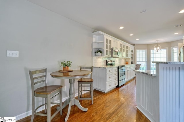 182 Roundstone Dr, Inman, SC 29349 - kitchen with appliances with stainless steel finishes, open shelves, tasteful backsplash, wood finished floors, and white cabinets