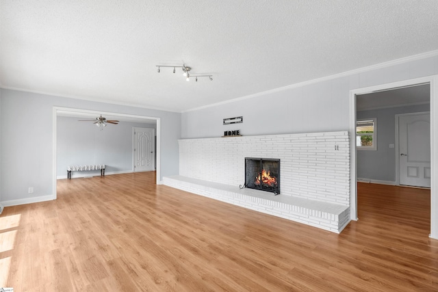 209 Boyd Ave, Simpsonville, SC 29681 - unfurnished living room with ornamental molding, a brick fireplace, light wood-type flooring, baseboards, and a textured ceiling