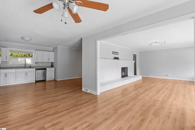 209 Boyd Ave, Simpsonville, SC 29681 - unfurnished living room with a textured ceiling, a sink, light wood-type flooring, a fireplace, and ceiling fan