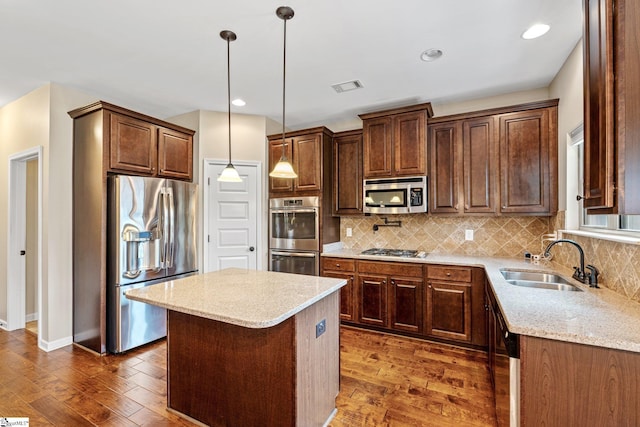 135 Adams Creek Pl, Simpsonville, SC 29681 - kitchen featuring stainless steel appliances, a sink, dark wood finished floors, light stone counters, and a kitchen island