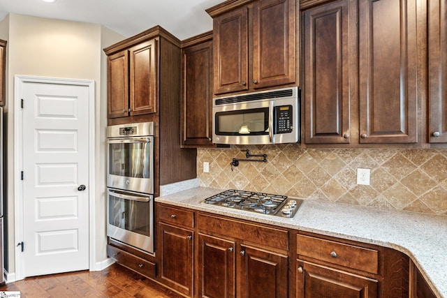 135 Adams Creek Pl, Simpsonville, SC 29681 - kitchen with stainless steel appliances, backsplash, light stone counters, dark brown cabinets, and dark wood-style flooring