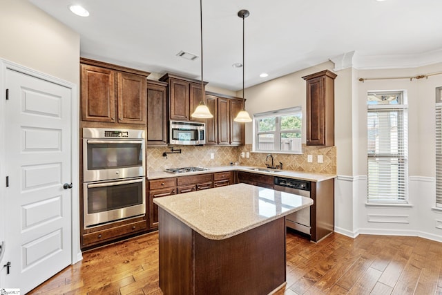 135 Adams Creek Pl, Simpsonville, SC 29681 - kitchen featuring stainless steel appliances, a sink, hardwood / wood-style flooring, light stone countertops, and pendant lighting