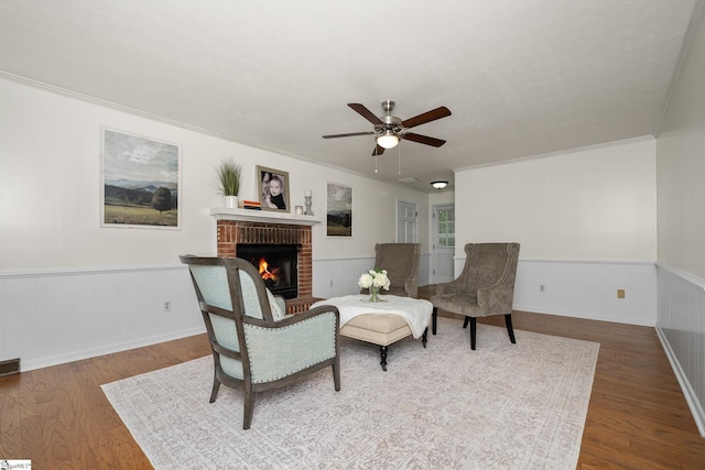 101 Shagbark Cir, Simpsonville, SC 29680 - living area featuring a brick fireplace, wood finished floors, ceiling fan, wainscoting, and ornamental molding