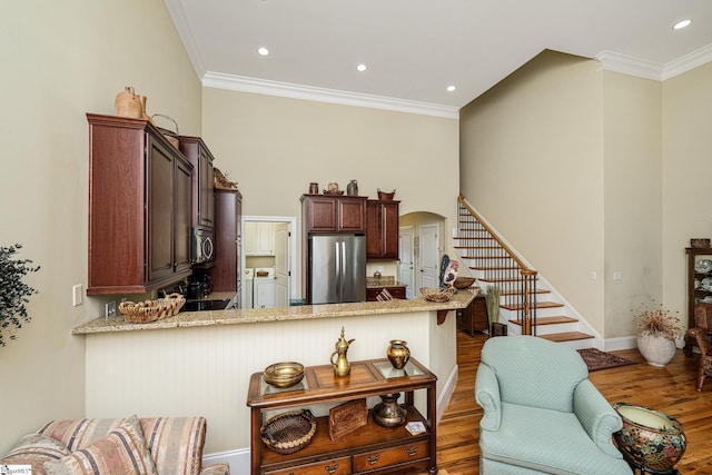225 Chickadee Trl Unit B, Easley, SC 29642 - kitchen featuring appliances with stainless steel finishes, washing machine and dryer, a peninsula, arched walkways, and wood finished floors