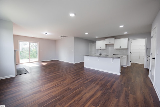 1305 Ledsham Ct, Greer, SC 29651 - kitchen with baseboards, light stone countertops, a kitchen island with sink, dark wood finished floors, and recessed lighting
