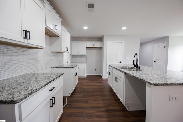 1305 Ledsham Ct, Greer, SC 29651 - kitchen featuring a sink, dark wood-style floors, light stone countertops, backsplash, and an island with sink
