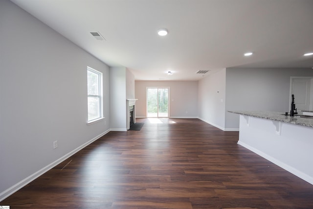 1305 Ledsham Ct, Greer, SC 29651 - unfurnished living room featuring baseboards, recessed lighting, dark wood-style flooring, a fireplace, and a sink