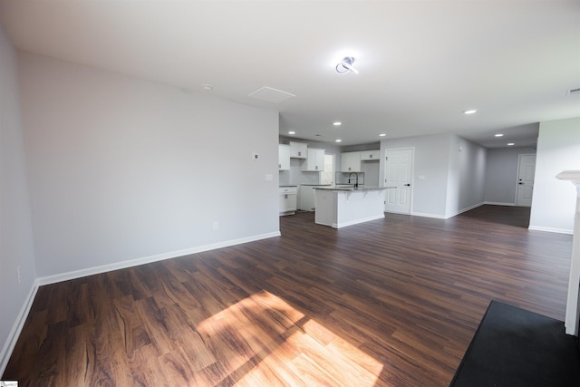1305 Ledsham Ct, Greer, SC 29651 - unfurnished living room with baseboards, dark wood-style floors, recessed lighting, and a sink