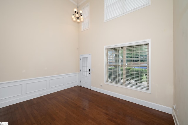 101 Kings Heath Ln, Simpsonville, SC 29680 - spare room with a chandelier, a towering ceiling, dark wood-style flooring, baseboards, and wainscoting