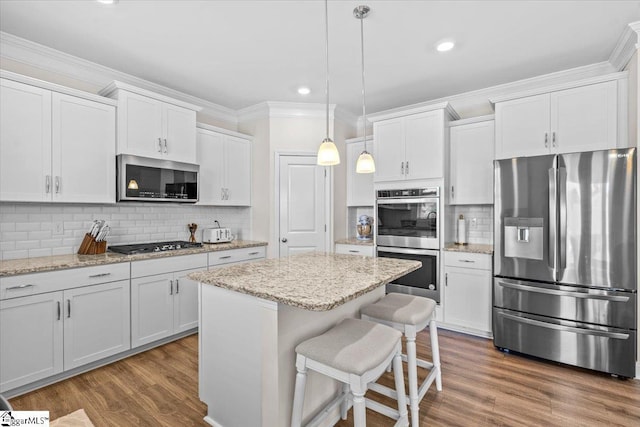 466 Fox Run Trl, Woodruff, SC 29388 - kitchen with appliances with stainless steel finishes, ornamental molding, white cabinetry, a kitchen island, and decorative backsplash