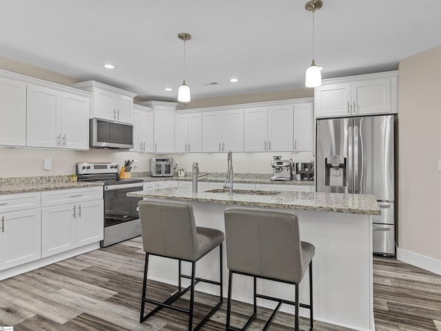 197 Falling Creek Rd, Spartanburg, SC 29301 - kitchen with stainless steel appliances, a sink, wood finished floors, white cabinets, and a kitchen breakfast bar