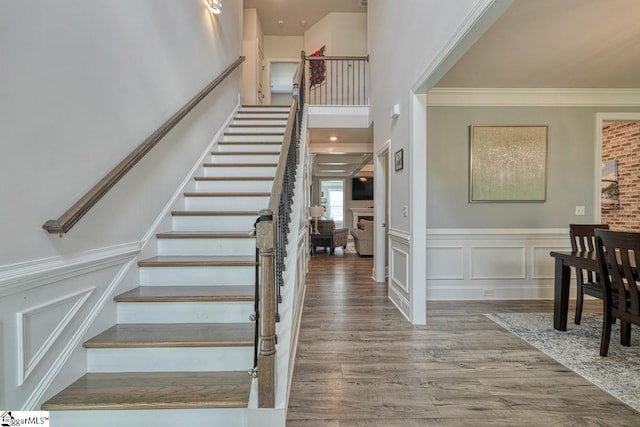 2 Stony Run Ln, Simpsonville, SC 29681 - stairs featuring wood finished floors, crown molding, a fireplace, a wainscoted wall, and a decorative wall